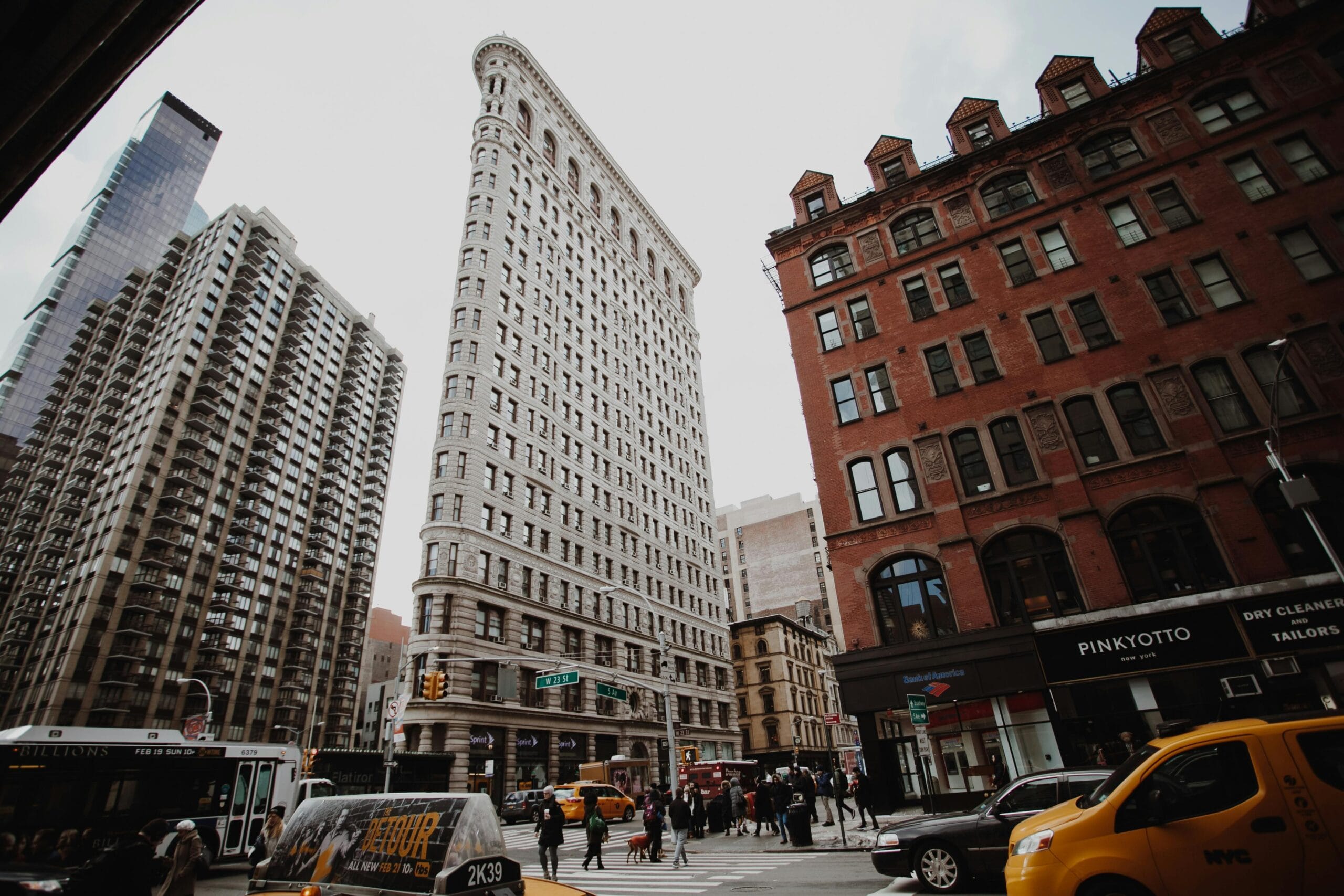 Dramatic cityscape view of New York's iconic Flatiron Building amidst bustling street traffic.